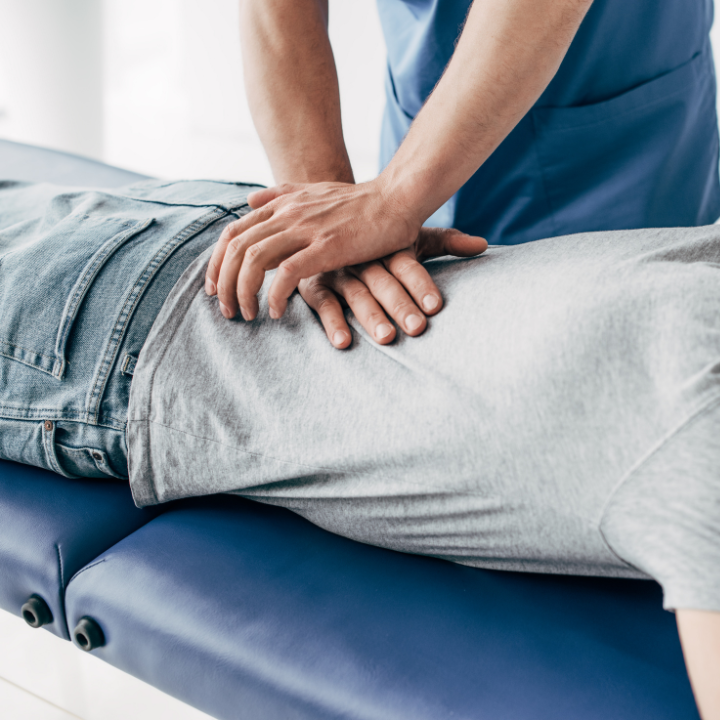 Un quiropractico realizando un ajuste postural en la espalda baja de un paciente